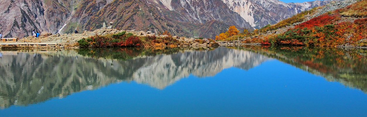 Stunning view of Hakuba’s autumn foliage at Tsugaike, with vibrant fall colors and mountain reflection on a clear blue lake in the Japanese Alps